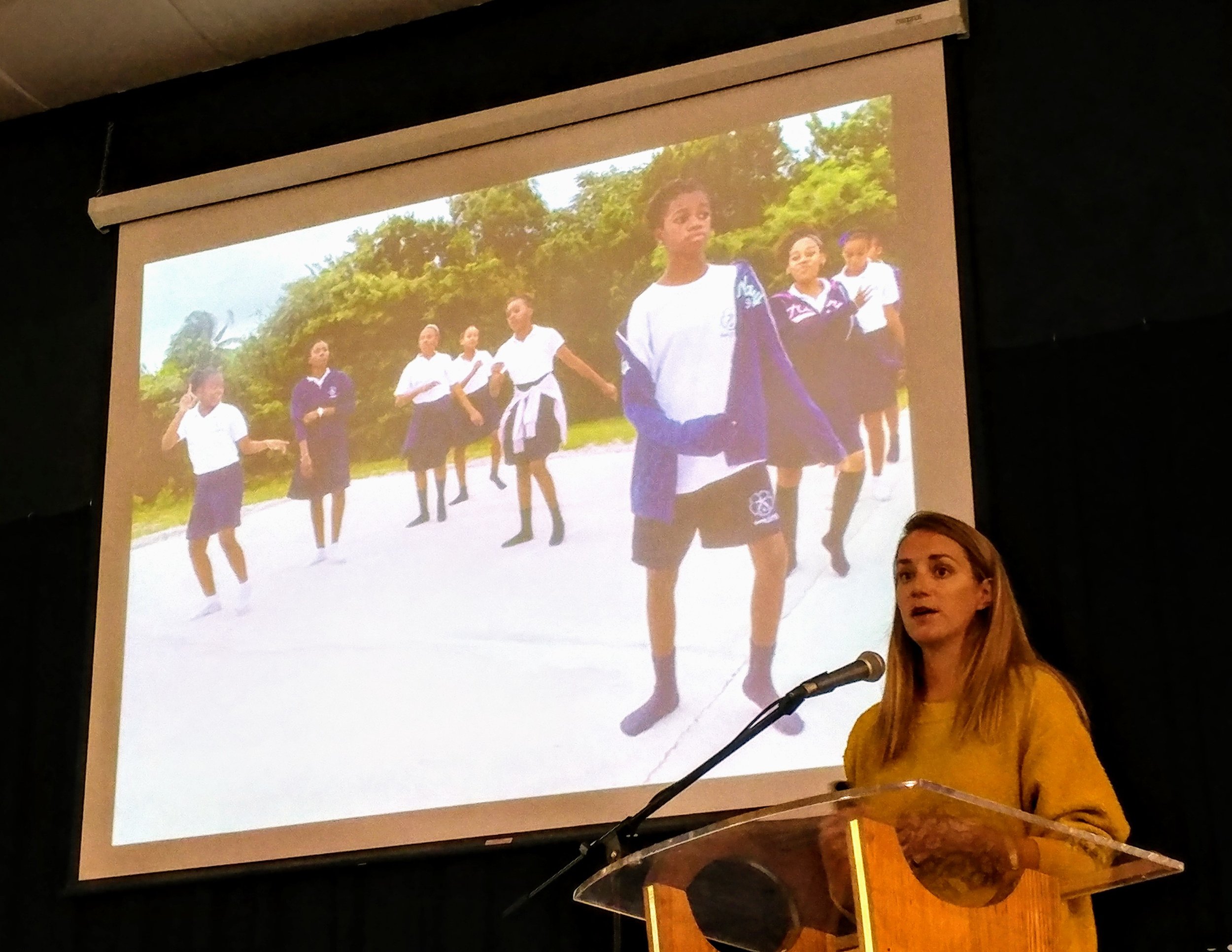 Candice Brittain presenting the parrotfish research, and showing an image of Deep Creek Middle School students preparing a skit to perform in their communities conveying the importance of parrotfish to the marine ecosystem.